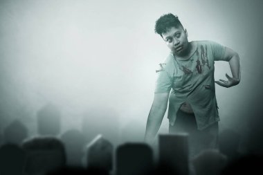 Mezarlıkta yürürken vücudunda kan ve yara olan korkunç bir zombi.