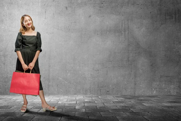アジアの女性は黒い壁の背景を持つショッピングバッグを持っています ブラック フライデーのコンセプト — ストック写真