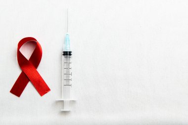 Kırmızı kurdele ve beyaz arka planlı şırınga. HIV AIDS kurdele farkındalığı