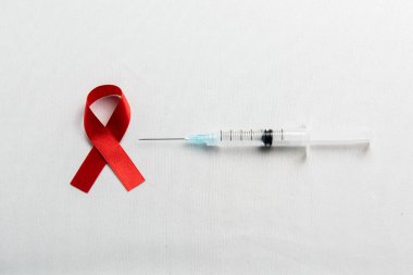 Kırmızı kurdele ve beyaz arka planlı şırınga. HIV AIDS kurdele farkındalığı