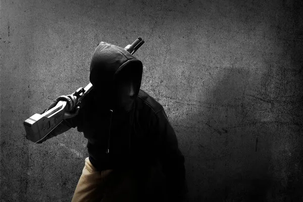 黒壁の背景を持つ散弾銃を持っている隠されたマスクの男 — ストック写真