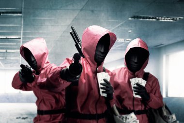 Pembe üniformalı bir grup suçlu ve soygundan sonra elinde av tüfeği tutan gizli bir maske.