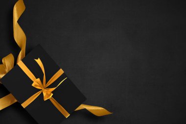 Siyah arkaplanlı altın kurdeleli siyah hediye kutusu. Kara Cuma konsepti
