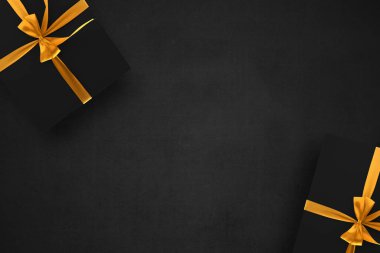 Siyah arkaplanlı altın kurdeleli siyah hediye kutusu. Kara Cuma konsepti