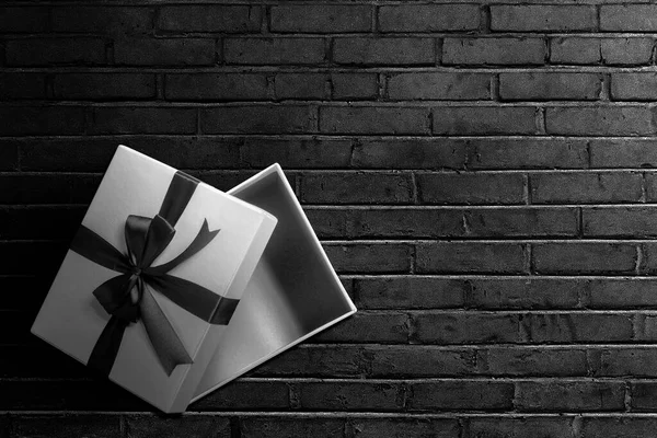 打开一个白色礼品盒 盒子上有一条黑色缎带 背景为黑色墙壁 黑色星期五概念 — 图库照片