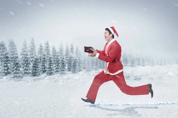 Азіат Костюмі Санти Біжить Тримаючи Подарунковий Ящик Сніговому Полі Сніговим — стокове фото