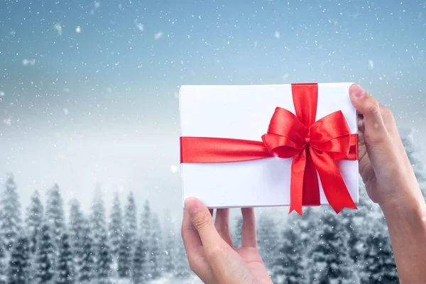 Рука Белой Подарочной Коробкой Красной Лентой Фоне Снега — стоковое фото