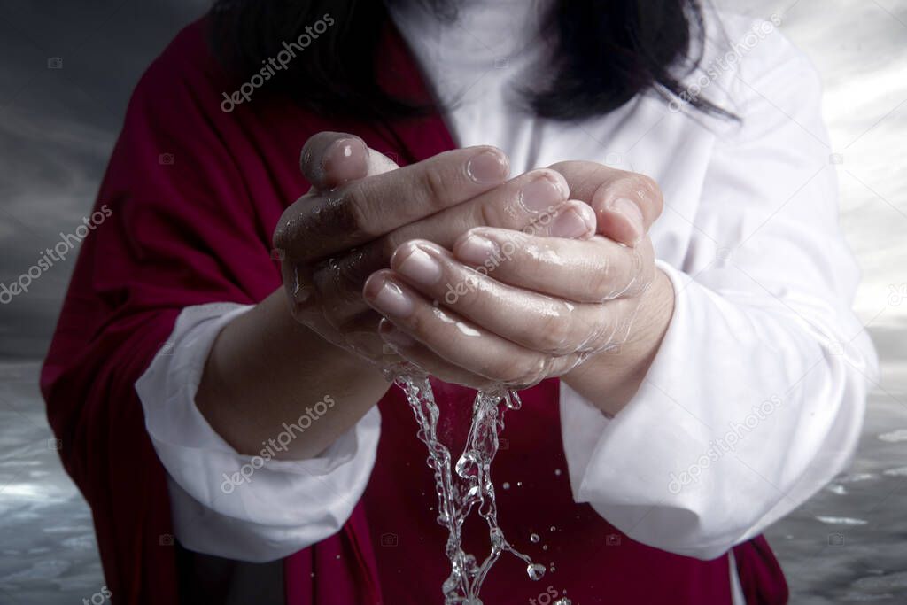Jesus Christ with open palm giving hold the water with dramatic background