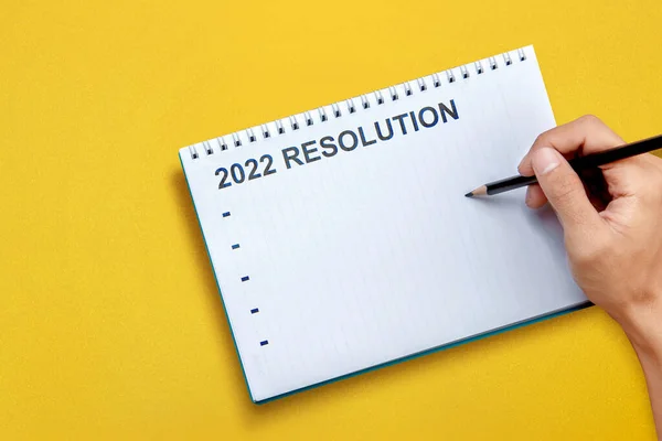 Human hand writes a list for 2022 resolution on the note book. Resolution of 2022. Happy New Year 2022