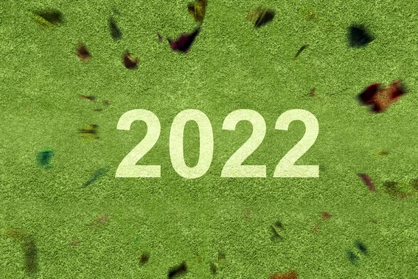 2022年緑の草の上にコンフェッティの背景を持つ 2022年あけましておめでとう — ストック写真
