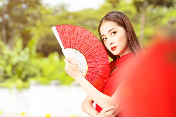 身穿旗袍的亚裔中国女人拿着扇子庆祝中国新年 新年快乐 — 图库照片