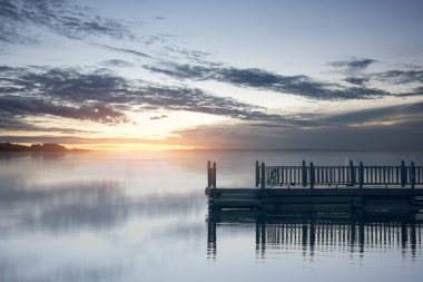 Göl kenarındaki ahşap rıhtımda dramatik bir arka plan var.