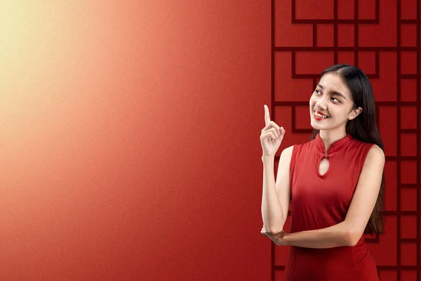 色の背景を持つ何かを指しているChengsamドレスでアジアの中国人女性 中国の旧正月 — ストック写真