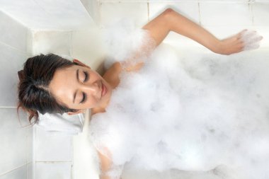 Asyalı kadın küvette dinleniyor.