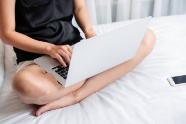 Yatakta dizüstü bilgisayar kullanan bir kadın.