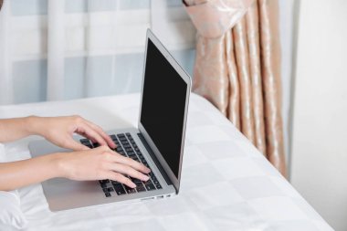Yatakta dizüstü bilgisayar kullanan bir kadın.
