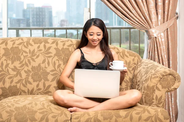 Femeia Asiatică Stând Timp Folosea Laptop Ținând Ceașcă Cafea Canapea — Fotografie, imagine de stoc