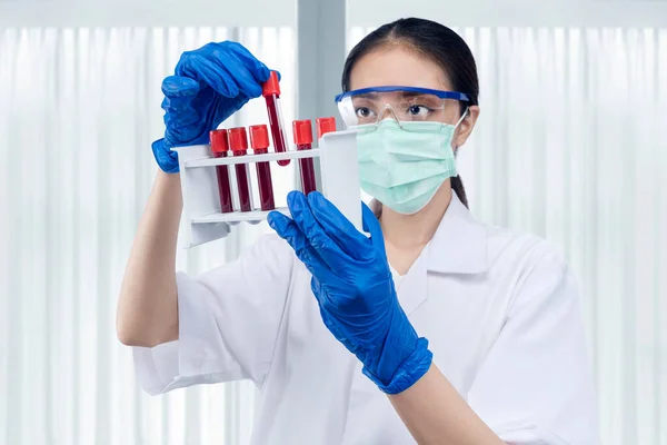 顔マスクと眼鏡を持つアジアの研究者女性は 研究室で医療チューブラックを保持 — ストック写真