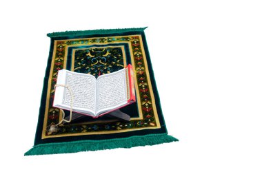 Kur 'an, beyaz arka planda izole edilmiş bir halının içinde ahşap bir yere açılır.
