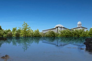 Göletli cami ve mavi gökyüzü arka planlı ağaçlar. Jakarta, Endonezya