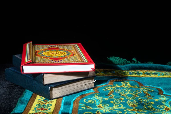 在黑暗背景下的祈祷毯上的古兰经 — 图库照片