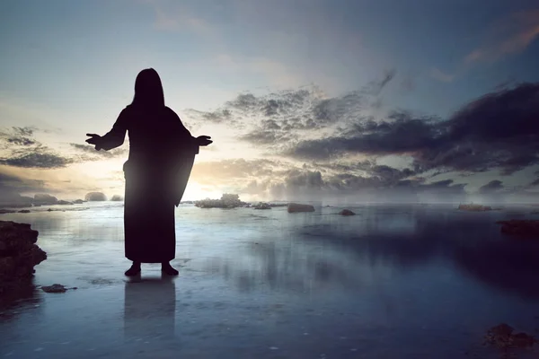 イエス キリストのシルエットが劇的な背景を持って水面に立っている — ストック写真