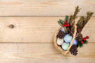 Tahta masadaki sepetin üzerinde renkli bir paskalya yumurtası. Mutlu Paskalyalar