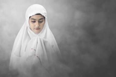 Maskeli Asyalı Müslüman kadın ellerini kaldırdı ve parlak bir geçmişle dua etti.