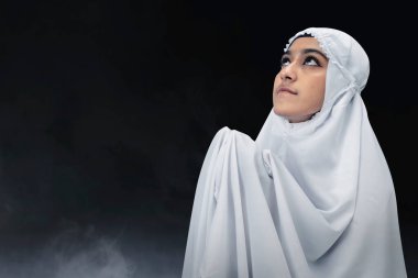 Peçeli Asyalı Müslüman kadın elini kaldırdı ve karanlık bir geçmişle dua etti.