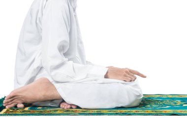Müslüman bir adamın beyaz arka planda izole edilmiş bir dua halısı üzerinde ibadet edişine yakından bakın.