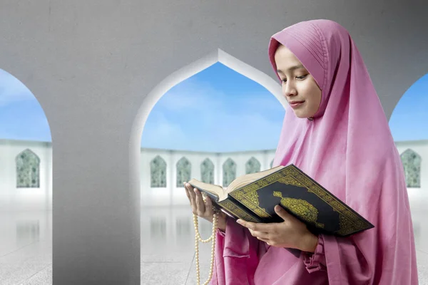礼拝用の玉を持ち モスクでクルアーンを読むベールに身を包んだアジア系ムスリム女性 — ストック写真