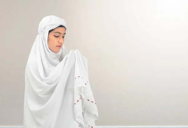 白い壁の背景で手を上げ祈りながらベール立っているアジアのイスラム教徒の女性 — ストック写真