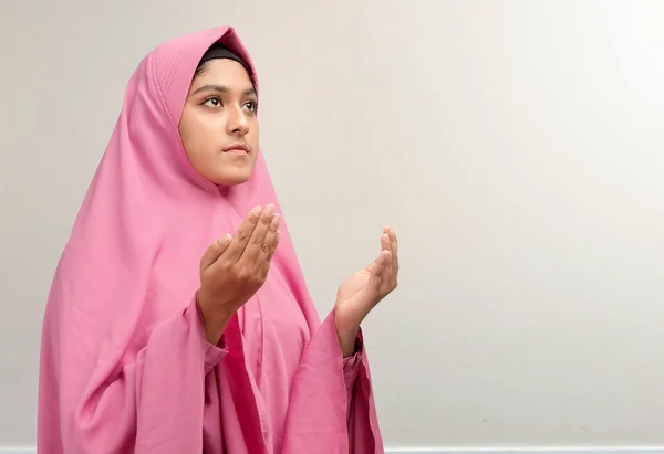 白い壁の背景で手を上げ祈りながらベール立っているアジアのイスラム教徒の女性 — ストック写真