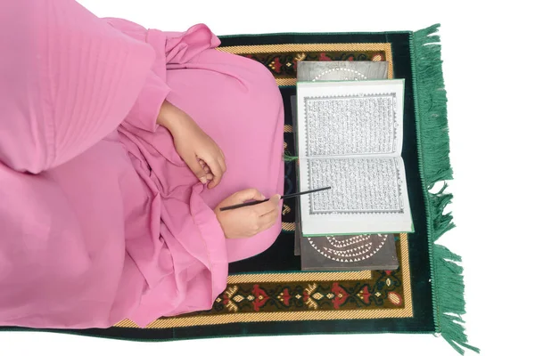 礼拝用の敷物の上に座っているベールにイスラム教徒の女性と白の背景に隔離されたクルアーンを読んで — ストック写真