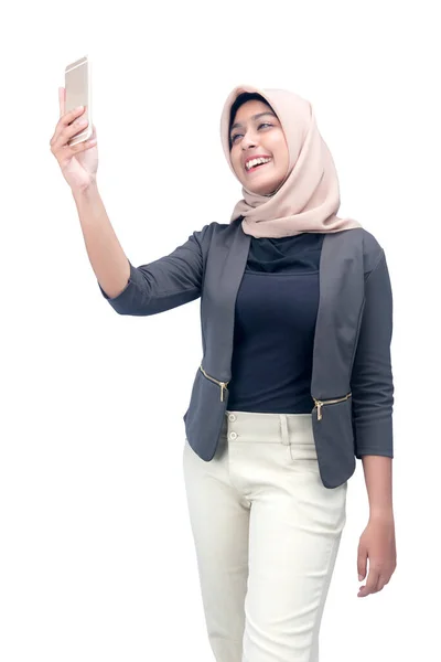 アジアのイスラム教徒女性ですスカーフ取りますA自撮りとともに彼女の携帯電話隔離された上の白い背景 — ストック写真