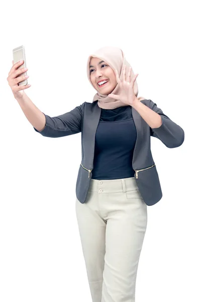 アジアのイスラム教徒女性ですスカーフ取りますA自撮りとともに彼女の携帯電話隔離された上の白い背景 — ストック写真