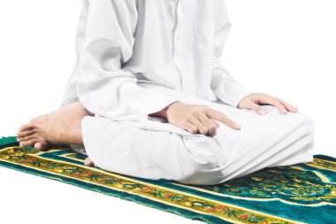 Beyaz arka planda izole edilmiş bir halının üzerinde namaz kılan müslüman bir adamın (namaz kılan) yakın görüntüsü