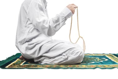 Müslüman bir adam elinde dua boncuklarıyla dua ederken beyaz arka planda izole bir şekilde namaz kılıyor.