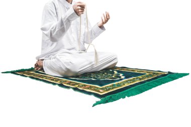 Müslüman bir adam elinde dua boncuklarıyla dua ederken beyaz arka planda izole bir şekilde namaz kılıyor.