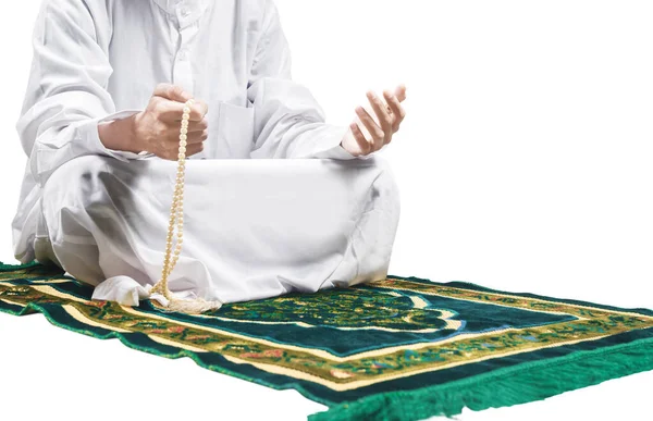 Müslüman bir adam elinde dua boncuklarıyla dua ederken beyaz arka planda izole bir şekilde namaz kılıyor.