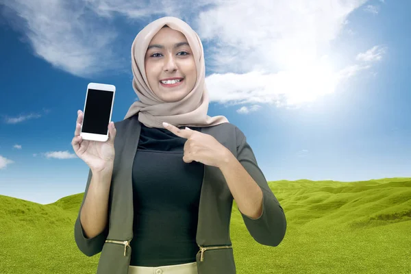 青い空の背景を持つ空白の携帯電話の画面を示すスカーフでアジアのイスラム教徒の女性 コピースペースのための空白の画面 — ストック写真