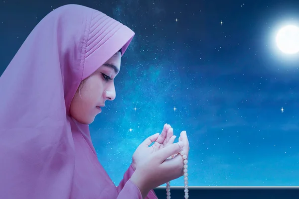 夜の風景を背景に手に祈りのビーズで祈るベールのアジアのイスラム教徒の女性 — ストック写真