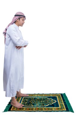 Keffiyeh 'li Müslüman bir adam beyaz arka planda izole edilmiş bir halı üzerinde namaz kılıyor.