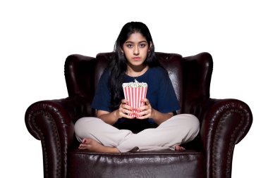 Kanepede oturan patlamış mısırlı Asyalı kadın beyaz arka planda izole edilmiş.