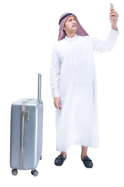 アラブ男身に着けていますKefiyeh見ますで携帯電話とともにスーツケースのために旅行のために隔離された白い背景 — ストック写真