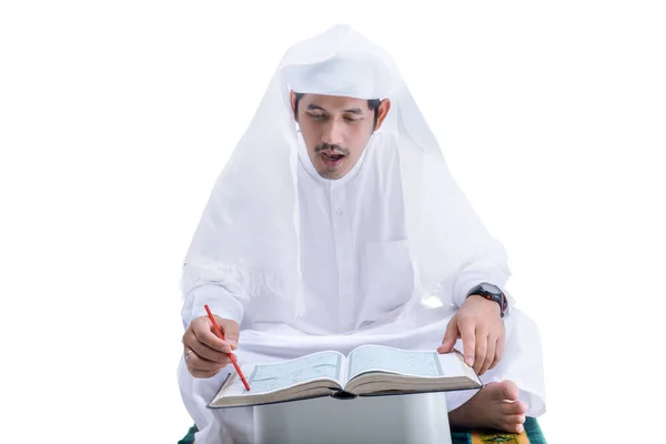 阿拉伯穆斯林男子坐在白色背景下孤立的祈祷毯上阅读 古兰经 — 图库照片