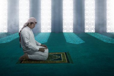 Mescid-i Haram 'ın içindeki halıda namaz kılmakta olan Kefiyeli Müslüman bir adam.