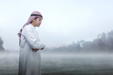 Kefiyye 'li müslüman bir adam açık havada namaz kılıyor.