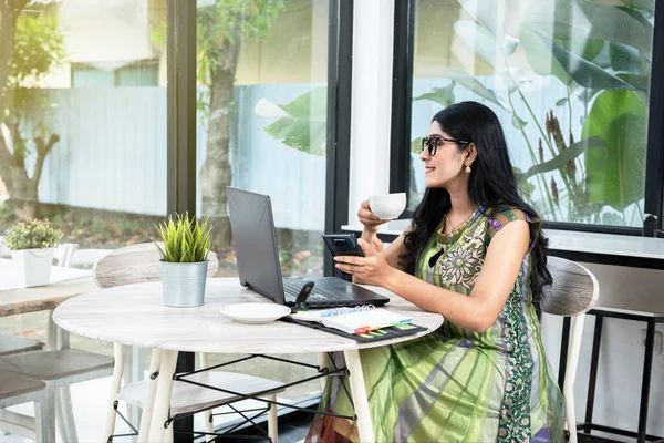 Mujer India Gafas Con Portátil Mesa Sosteniendo Taza Café Teléfono —  Fotos de Stock