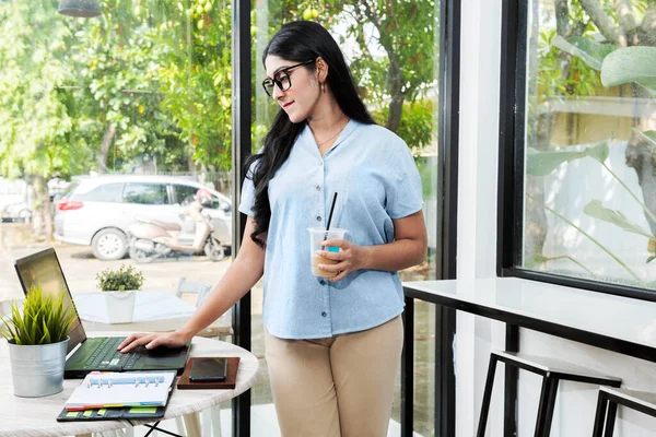 Mujer Asiática Gafas Pie Sosteniendo Café Mientras Usa Una Computadora —  Fotos de Stock